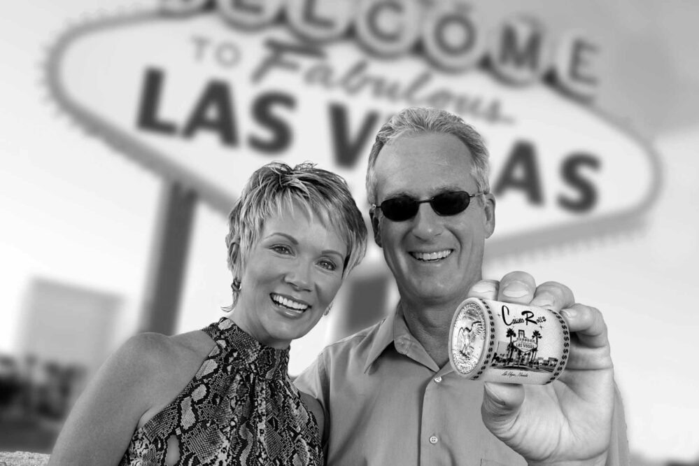 Couple holding a Casino Roll in front of the "Welcome to Las Vegas Sign"